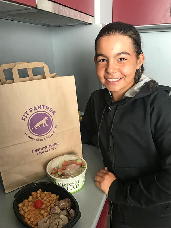 young girl in the kitchen with boxes of healthy food from Fit Panther